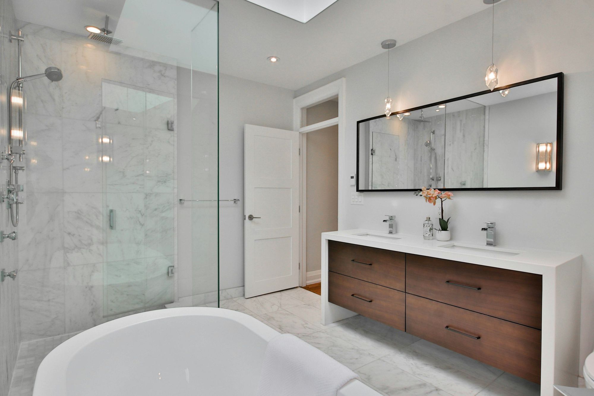 A walnut floating double vanity in a marble bath