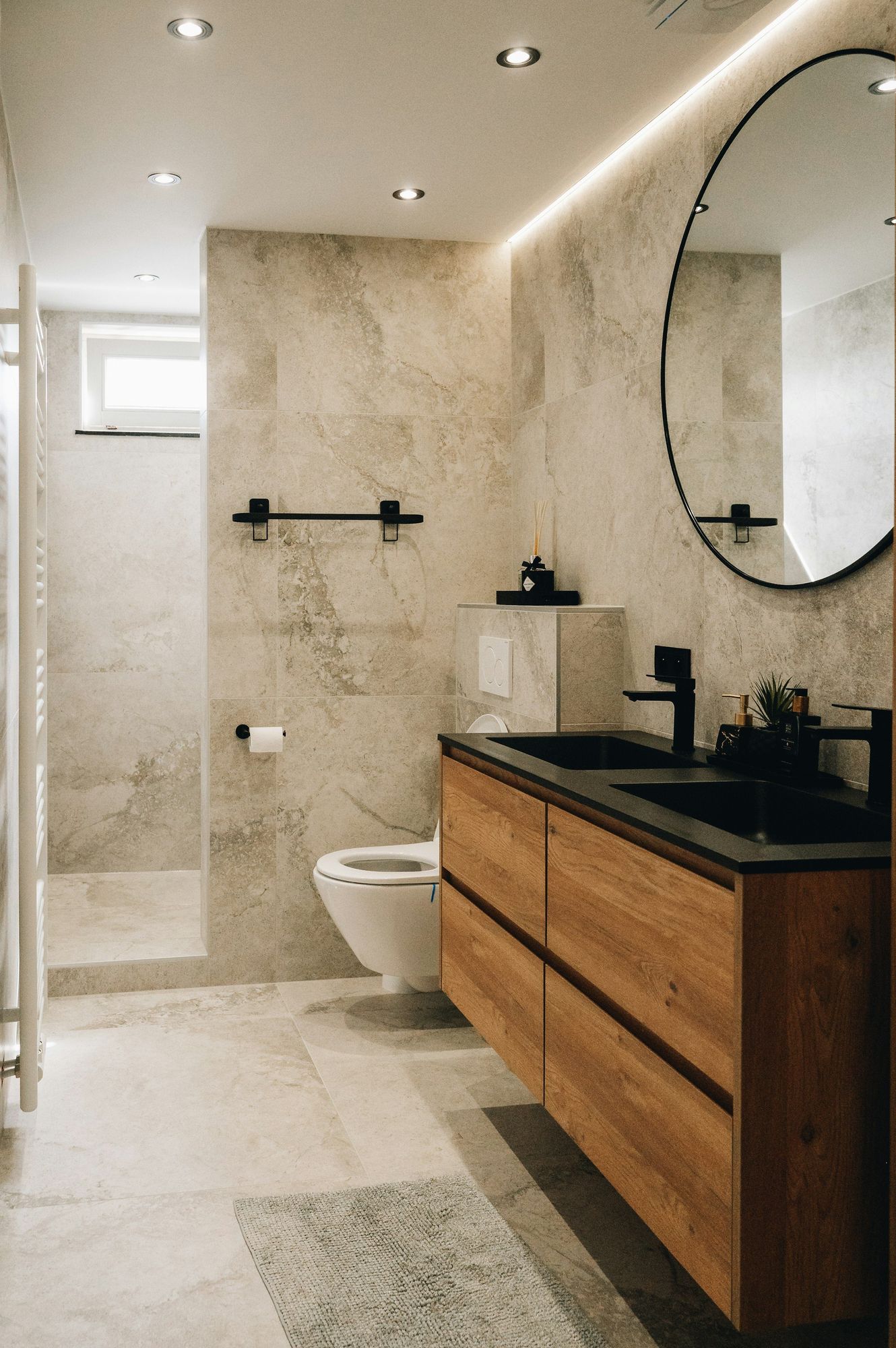 A walnut floating vanity under a round mirror